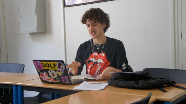 A study abroad student sitting at a desk and smiling while looking at a laptop