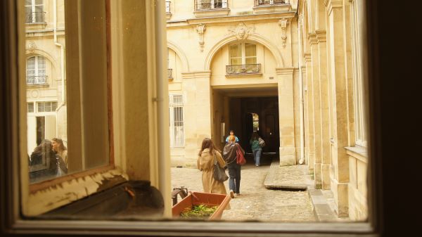 A group of study abroad students walking through a courtyard, as seen from behind through a window