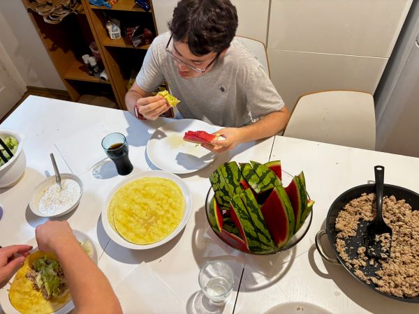 A study abroad student as seen from above sitting at a table covered in plates of food, eating a taco