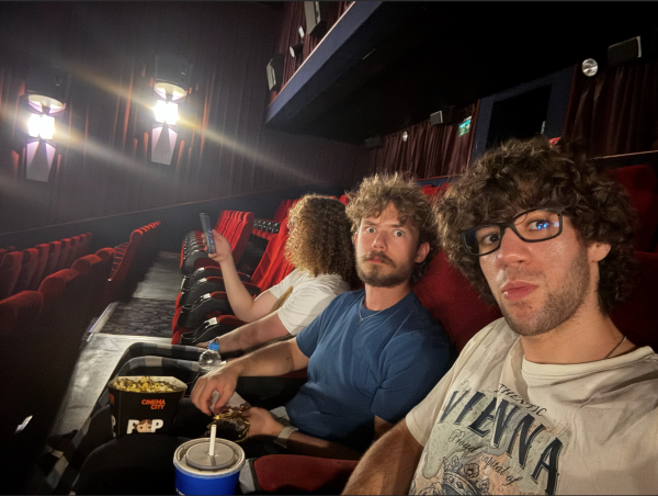 Two study abroad students taking a selfie while sitting in red seats in a movie theater