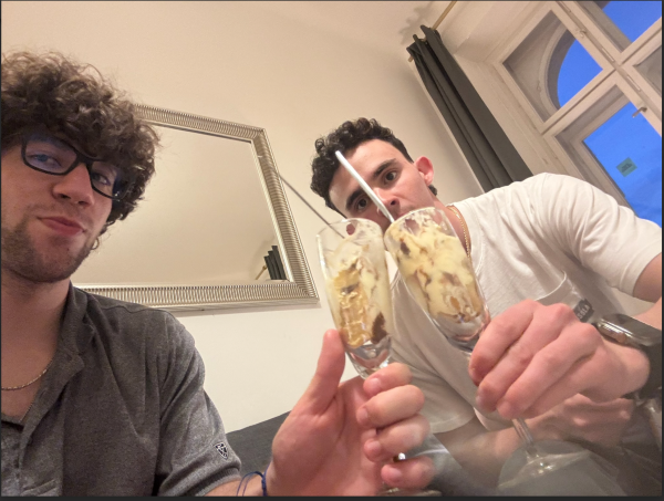 Two study abroad students smiling and holding champagne flutes full of a tiramisu dessert up to the camera