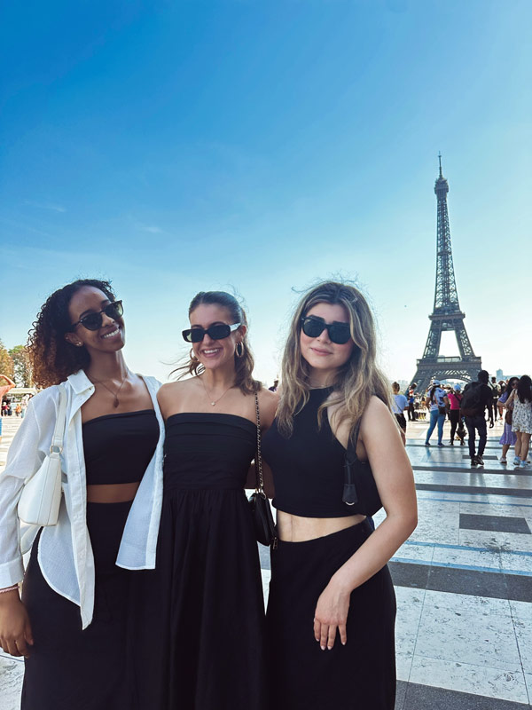 Three people pose in front of iconic landmark