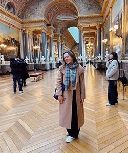 A person in a long coat in a large room with statues