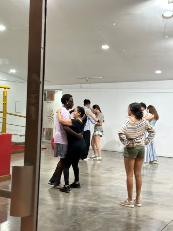 A group of study abroad students dancing in pairs in an indoor space