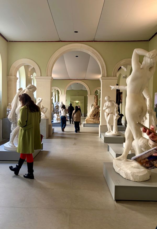 The interior of an art museum featuring various large white marble statues of human figures