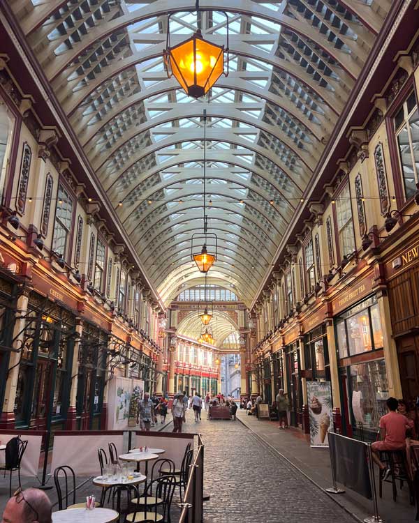 A glass ceiling with people walking around with Leadenhall Market in the background