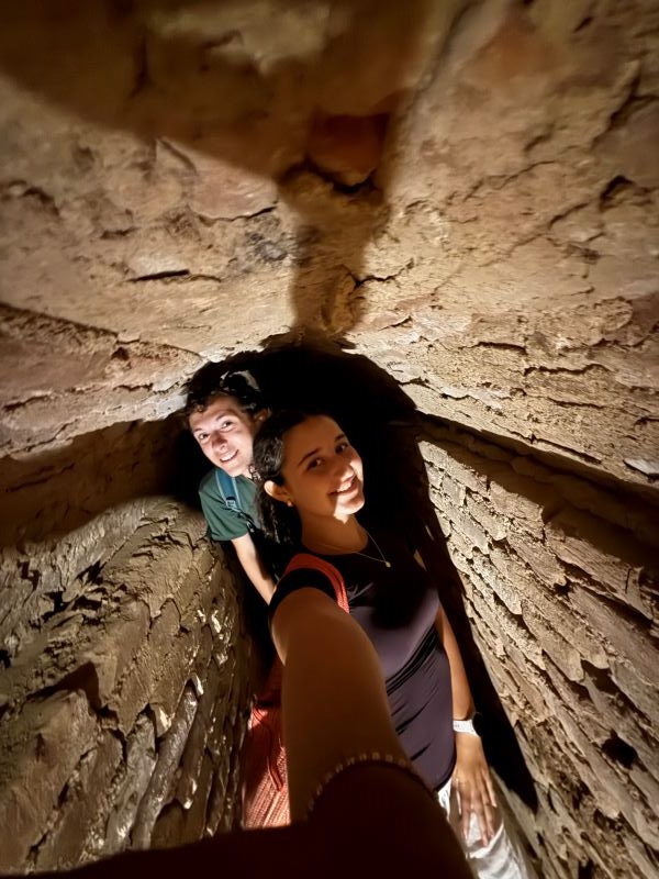 Two study abroad students taking a selfie and smiling at the camera in a narrow space between two brick walls