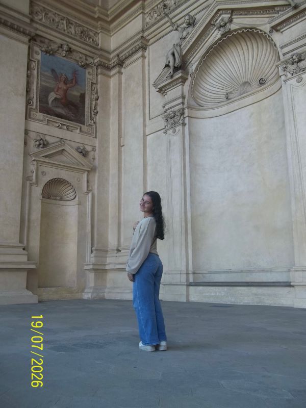 A study abroad student standing indoors and smiling at the camera