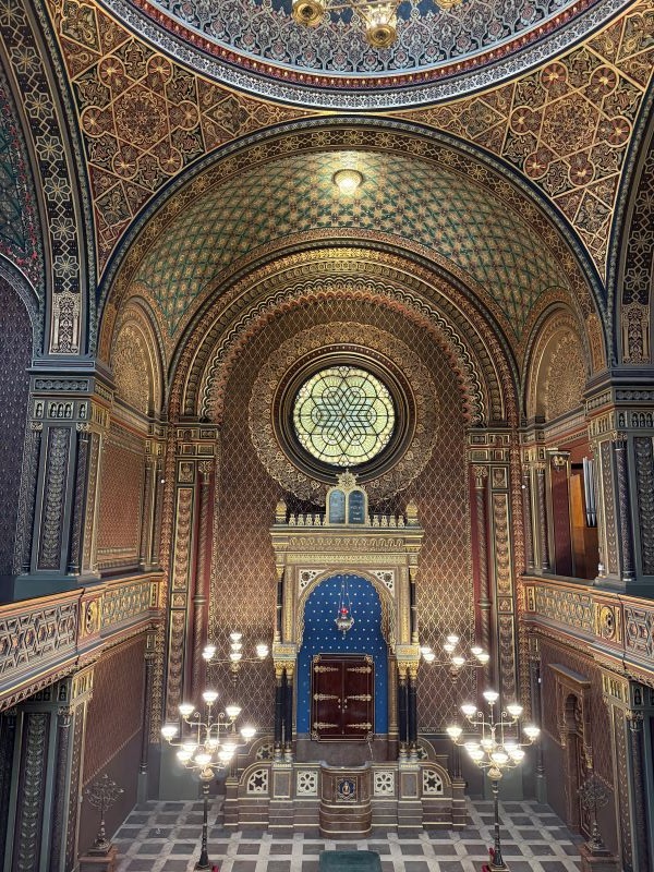 The interior of a large, intricately decorated building featuring a centerpiece and large standing candelabras