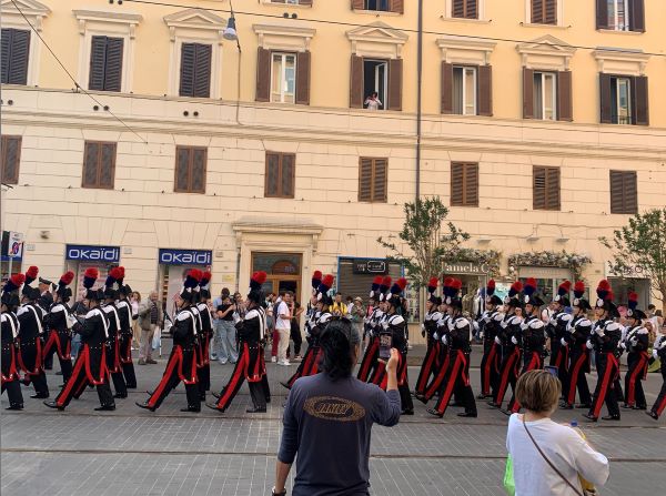 A parade of people dressed in red, white, and black uniforms walking down a city street