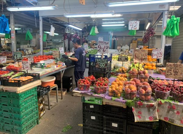 The interior of a small grocery store featuring tables full of fresh produce
