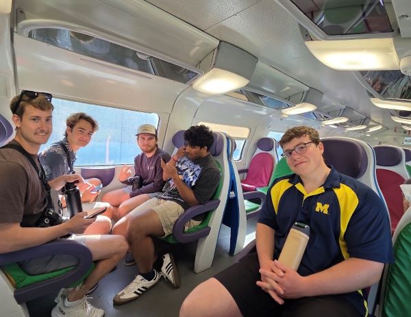 A group of study abroad students sitting inside a train and smiling at the camera