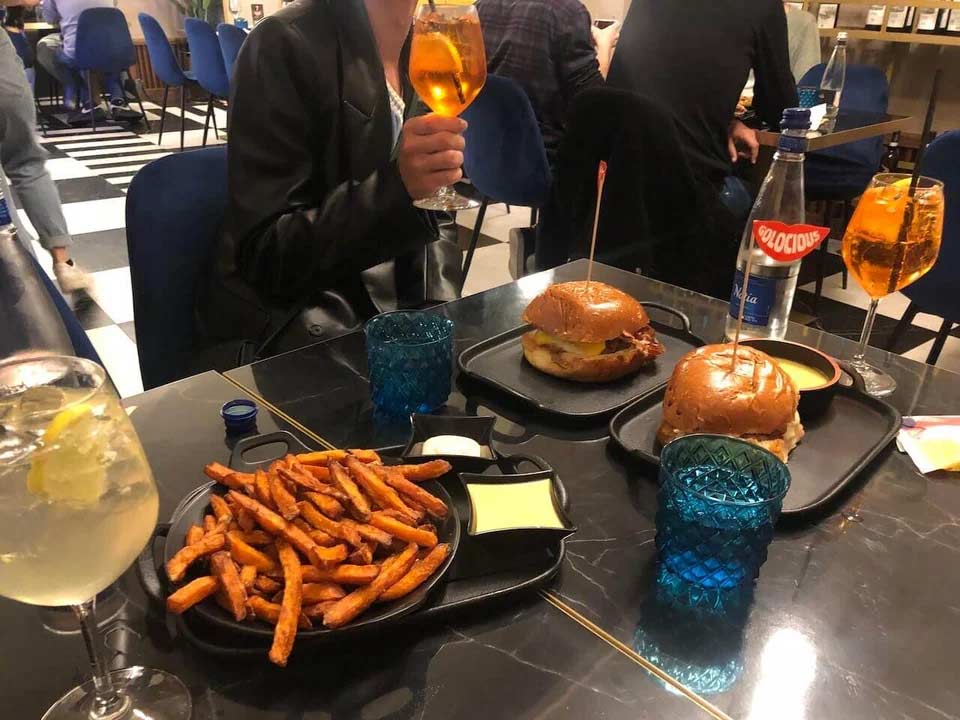 Burgers and sweet potato fries on a black table with a cup of water