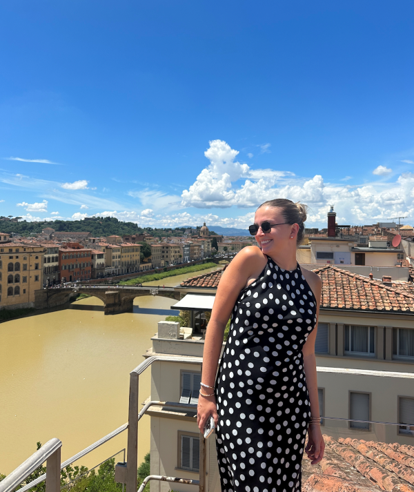 Study abroad student posing for photo on roof with the city and the Arno in the background