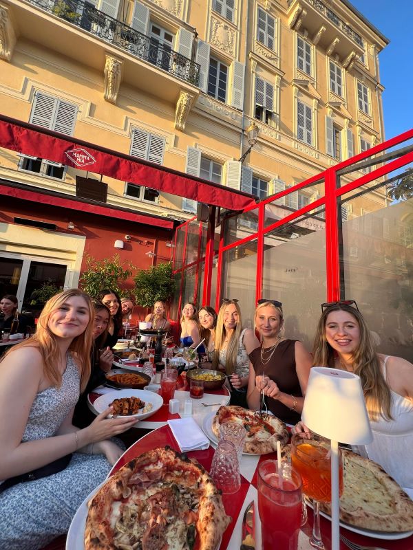 Group of study abroad students eating pizza at restaurant 