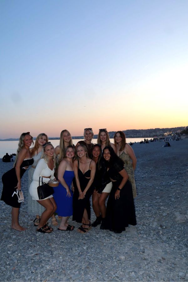 Group photo of 11 study abroad students on the beach at sunset