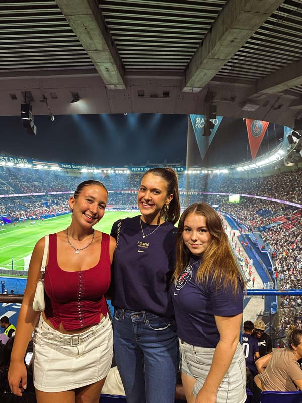 three people pose at a futbol stadium