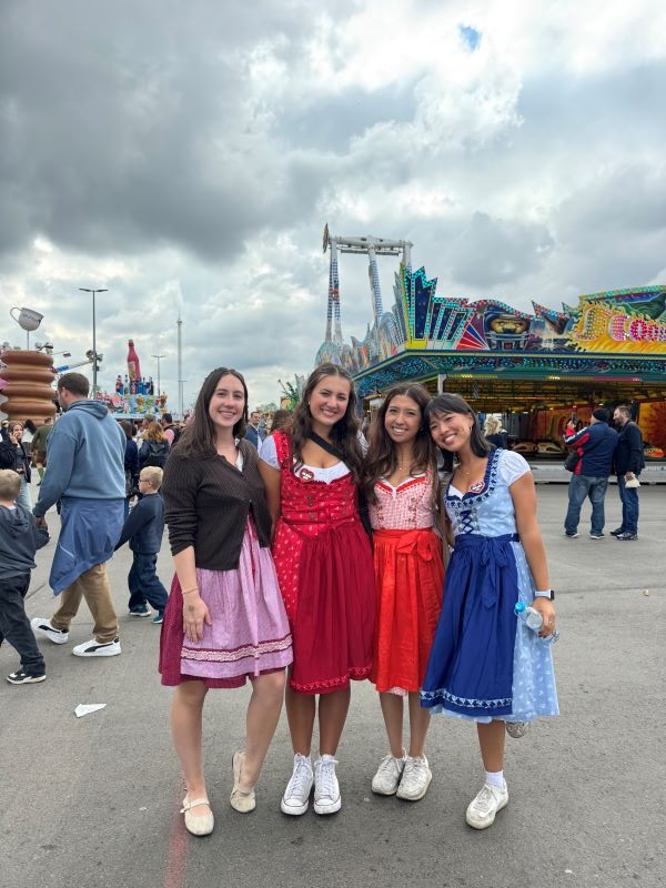 Four study abroad students in brightly colored dresses smiling at the camera in an outdoor setting