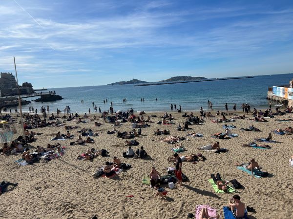 People scattered about a sandy beach in front of a large body of water