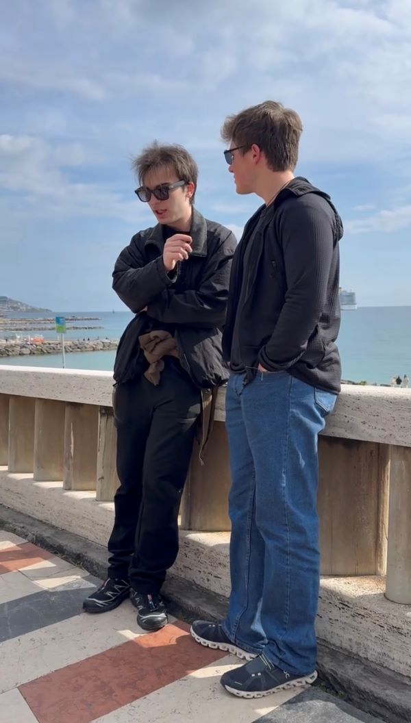 A study abroad student standing next to another person who is holding a small microphone up to the student and speaking with them