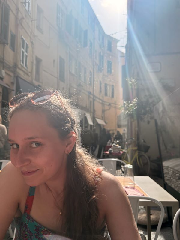 A study abroad student seen close up sitting at a restaurant table outdoors and smiling while looking at the camera