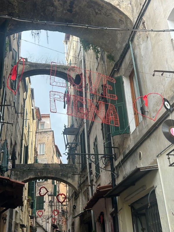 A city street as seen from below hemmed in by tall old sand-colored buildings on either side
