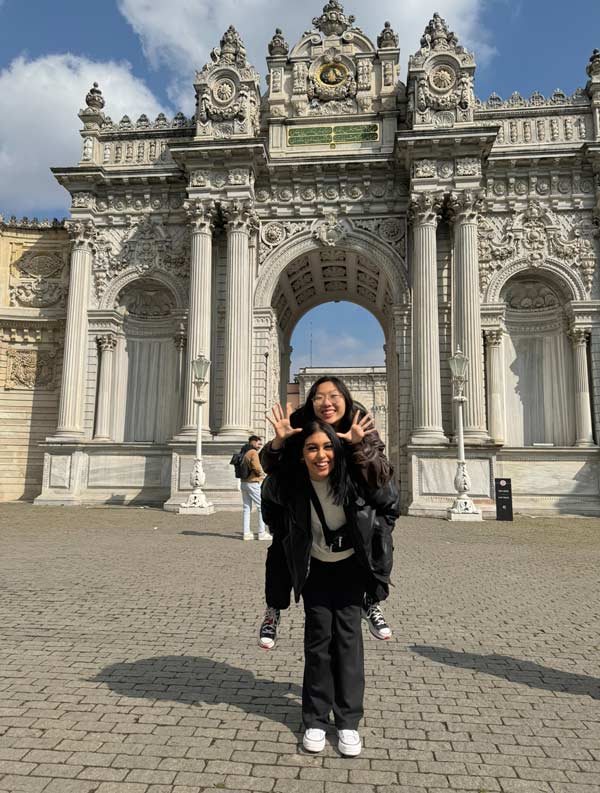 A study abroad student holding a person in front of a large stone archway