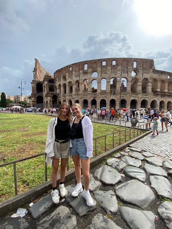 Two women posing for a picture in front of a large stone building