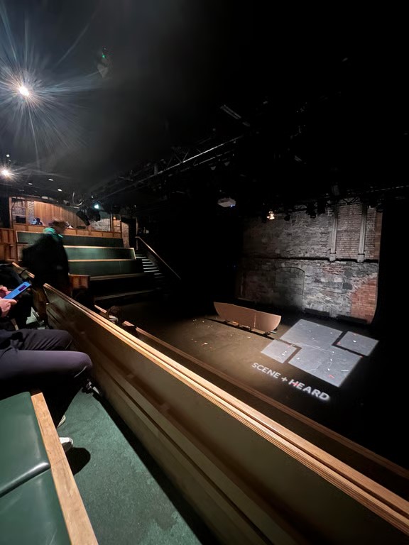 A theater stage as seen from above in an indoor space with the words