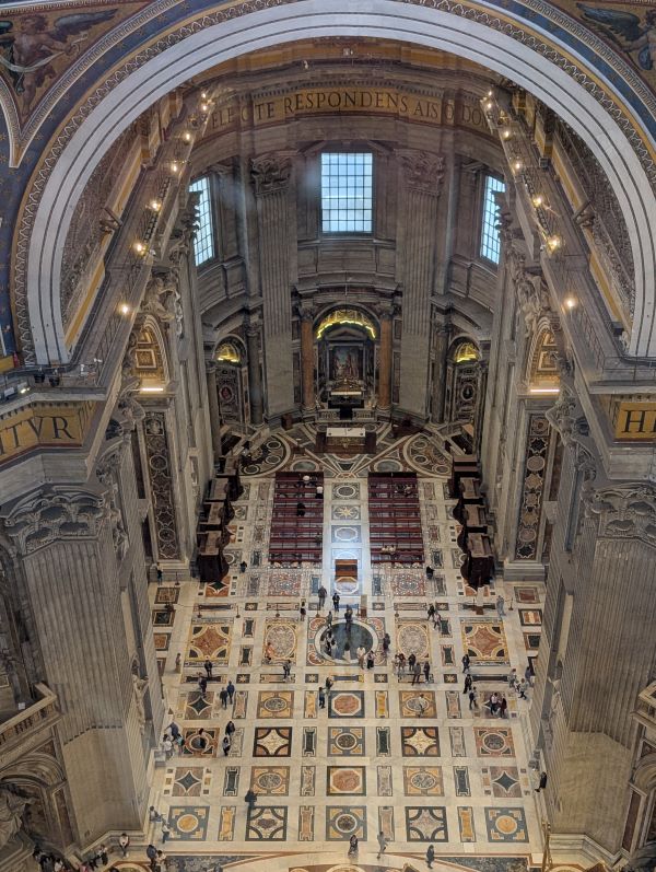 An ornate building interior with people walking around it as seen from high above