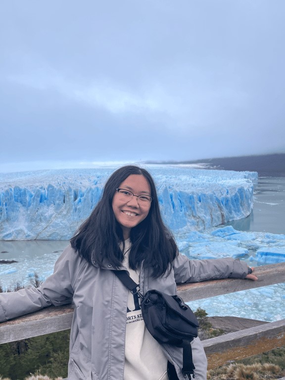 person standing smiling by glacier