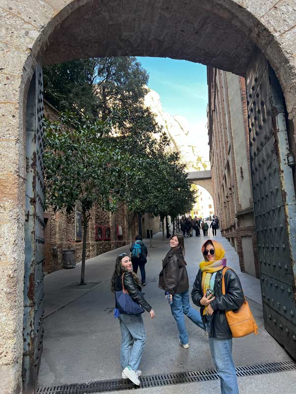 A group of study abroad students under a stone archway smiling at the camera