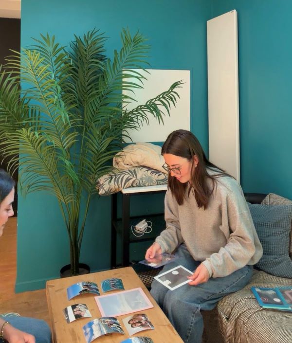 Two study abroad students sitting on a couch at a small table and looking at various photos