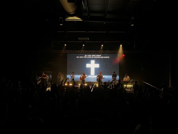 Photo of Christian band playing music on stage in dark lit room