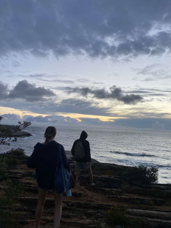 Study abroad students walking the coast as the sun goes down