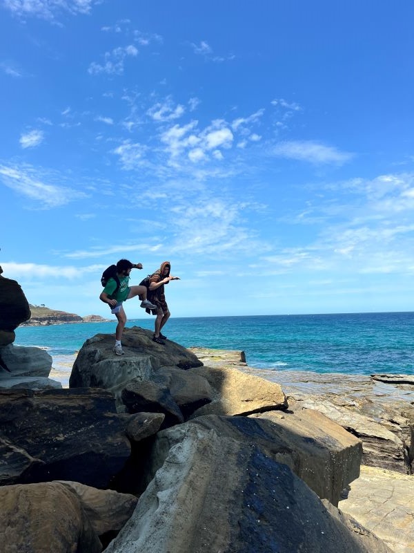 Two study abroad students playing around on rocks by ocean