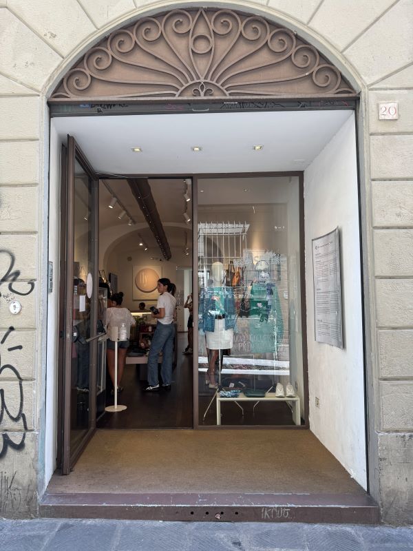 The entrance to a small store with mannequins in the window and people seen inside