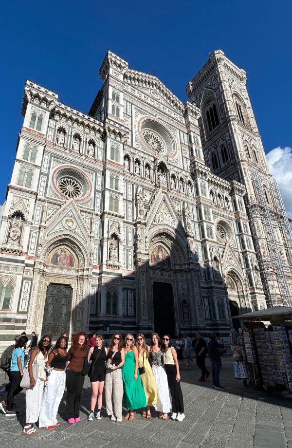 A group of study abroad students standing together outside of a large intricately carved white building