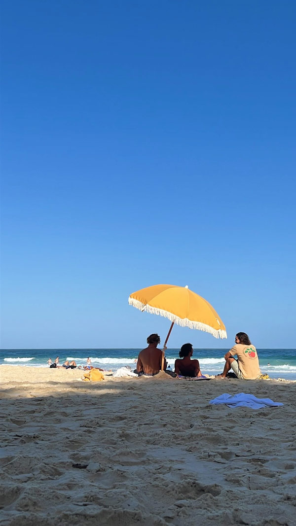 People sitting on the beach under an umbrella