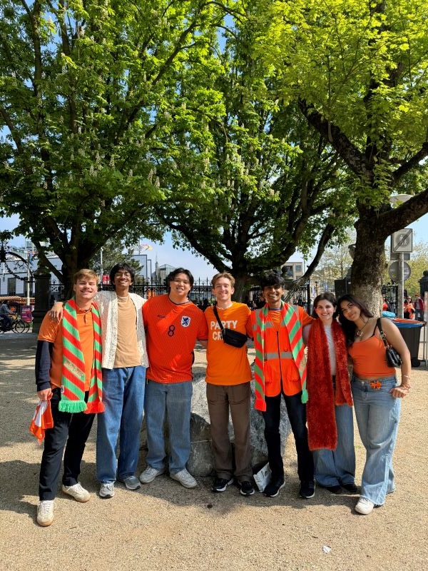 Seven study abroad students wearing orange and posing for photo