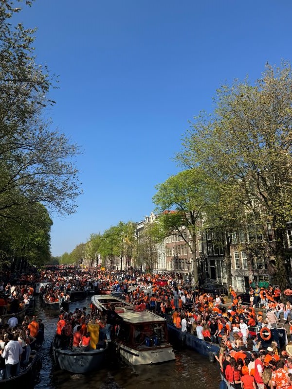 Amsterdam canal filled with boats and large crowds of people wearing orange