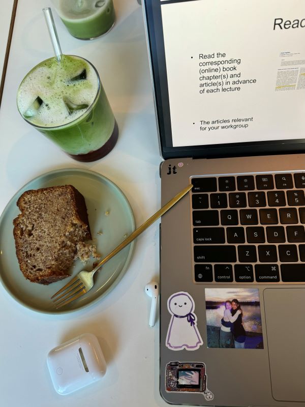 Iced matcha latte with pastry and laptop with earphones