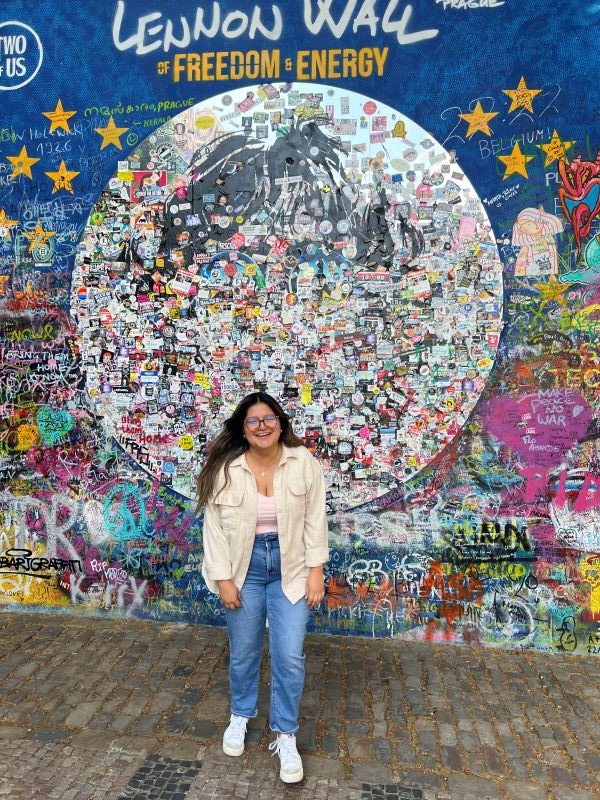 Study abroad student standing in front of the Lennon Wall