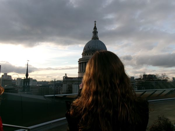 A study abroad student with blonde hair turned away from the camera and looking toward a tall church