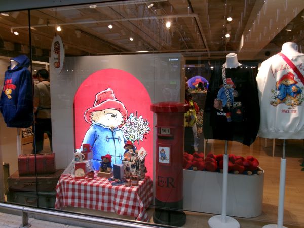 A shop window with merchandise including toys, shirts, and mugs all featuring a toy bear