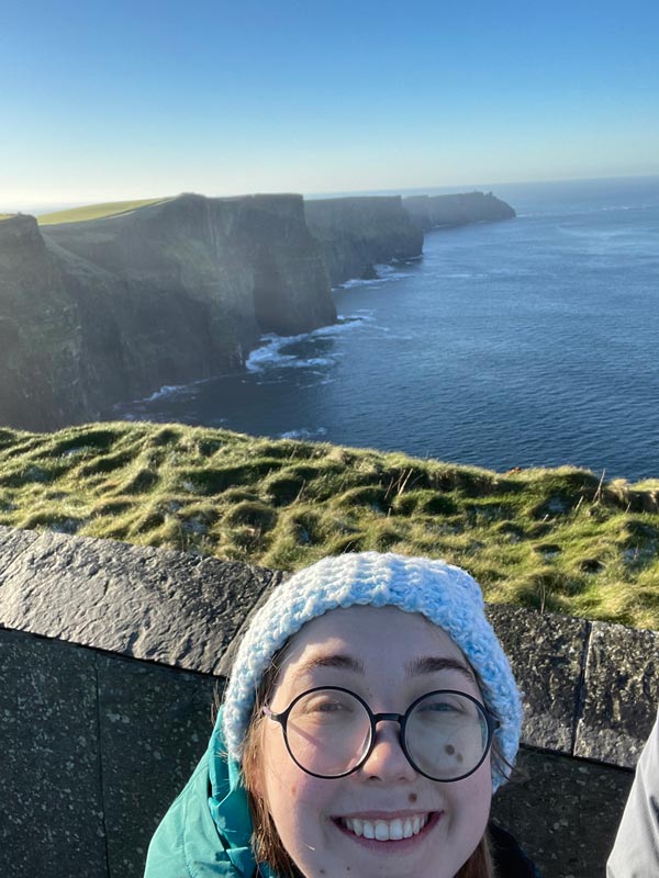 A study abroad student taking a selfie with a cliff and water