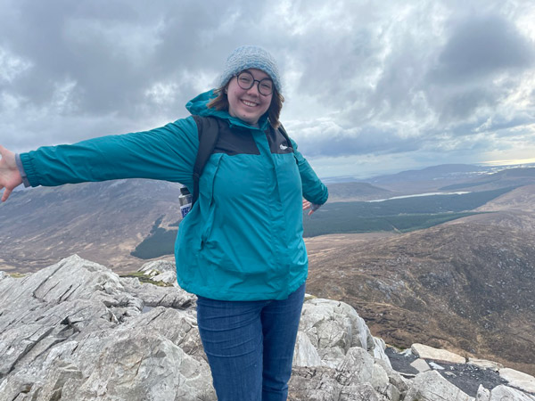 A study abroad student standing on a mountain with their arms out