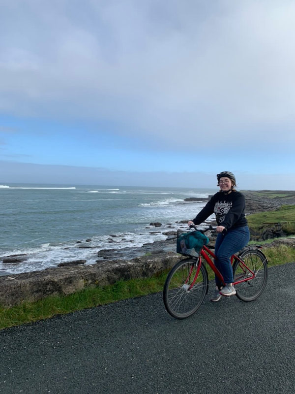 A study abroad student riding a bicycle on a road next to a body of water