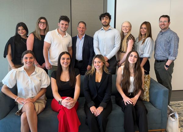 A group of pre-law students and several professionals standing together in a group indoors and smiling at the camera