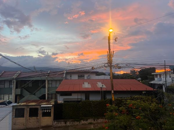 A group of buildings seen underneath a sunset of orange light and gray clouds